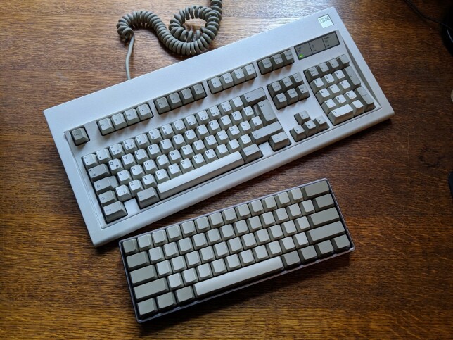 To tastaturer med forskjellig fysisk format. Det øverste er et fullstørrelse “IBM Model M” tastatur (100%), mens det nederste er et 60% “V60” tastatur.