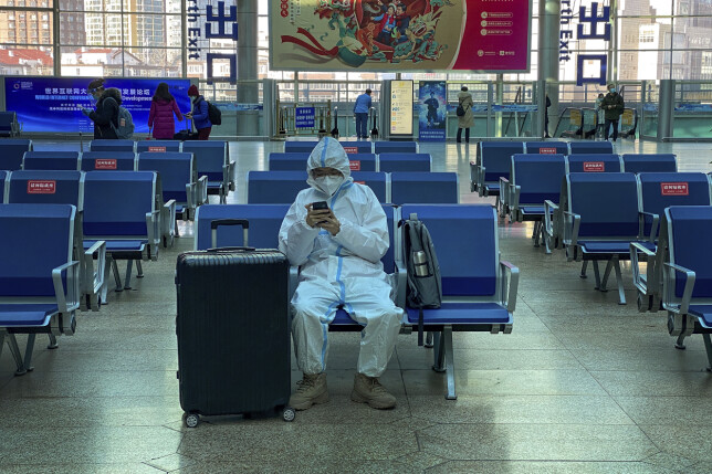 Her: En reisende med beskyttelsesutstyr venter på toget i Beijing.📸: AP Photo/Andy Wong