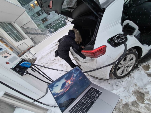 Backendutvikler May Helen Storvik (med hodet i bagasjerommet) debugger elbil-lading vinteren 2021. 📸: Elton Mobility
